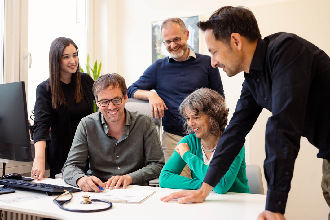 Das Team von meditz - Fachärztinnen und Fachärzte - berät sich mit Begeisterung gemeinsam an einem Schreibtisch.